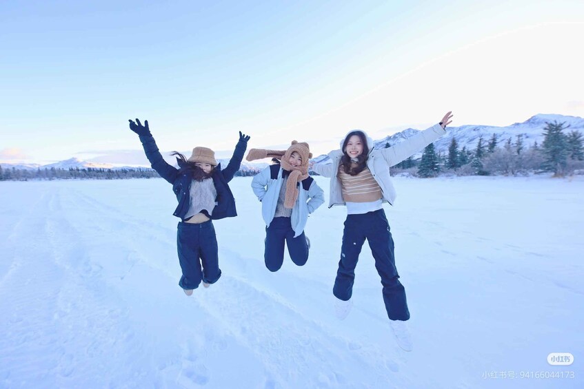 Three people jumping in a snowy landscape with mountains in the background. 5