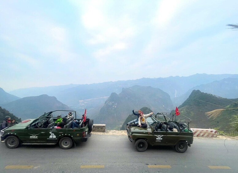 Two military vehicles on a road with a mountainous landscape in the background. 1