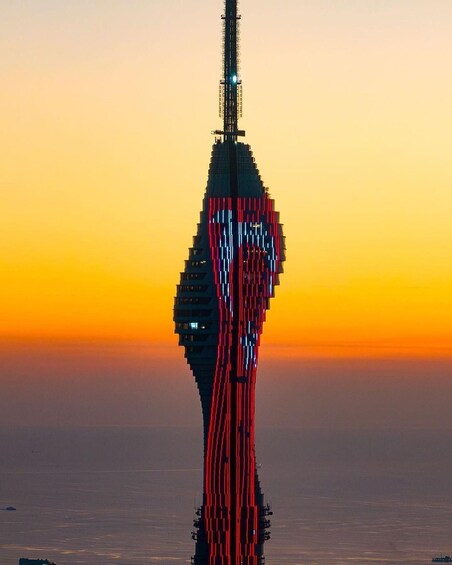 A tower with a unique design, illuminated against a sunset sky. 2