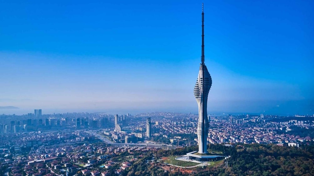 A tall tower with a spiral design, surrounded by a cityscape and greenery. 1