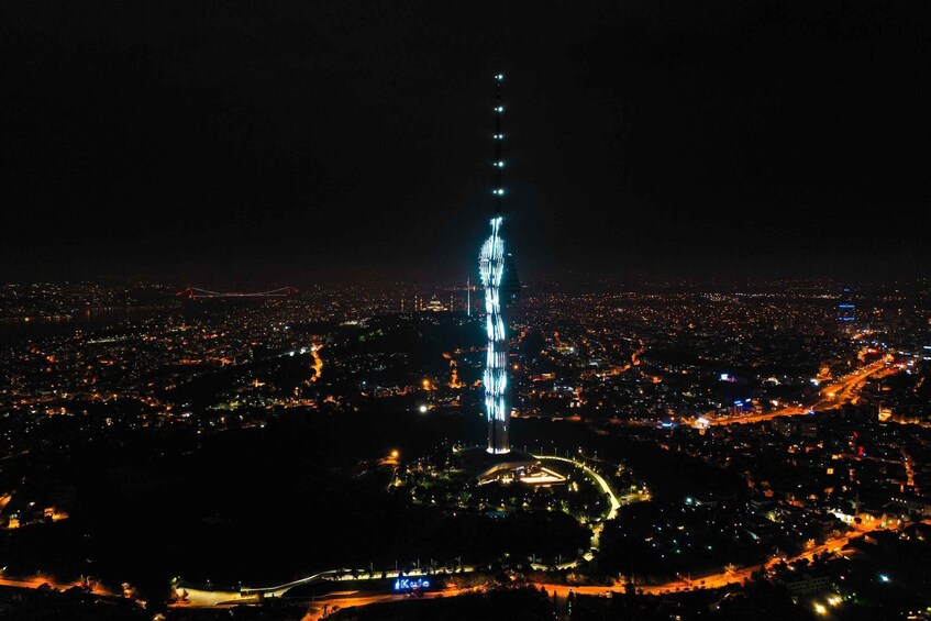 A cityscape at night with a prominent illuminated tower and surrounding urban area. 3