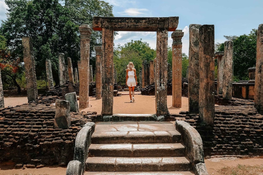 A person walking through ancient stone ruins with columns and steps. 5