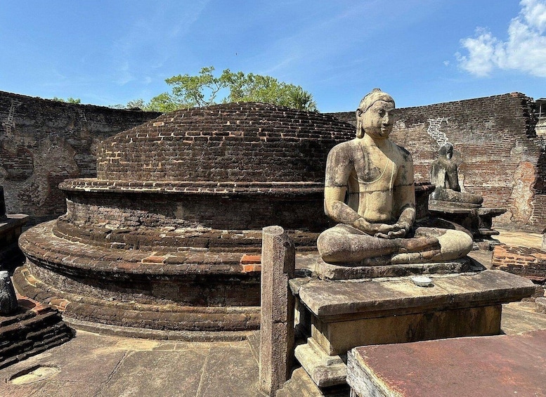 An ancient stone statue of a seated figure in a meditative pose, surrounded by ruins of a brick structure. 2