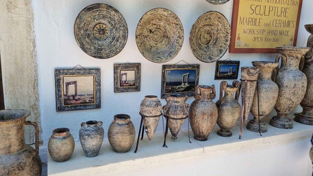 A variety of pottery and sculptures displayed on a wall, including vases and plates. 1