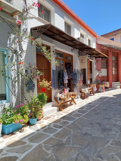 A cobblestone street with a shop displaying textiles and baskets. 2