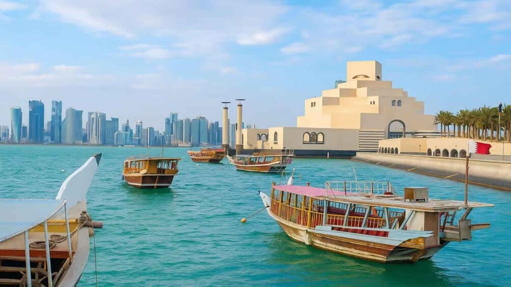 Traditional wooden boats docked near a modern city skyline with a prominent mosque. 1