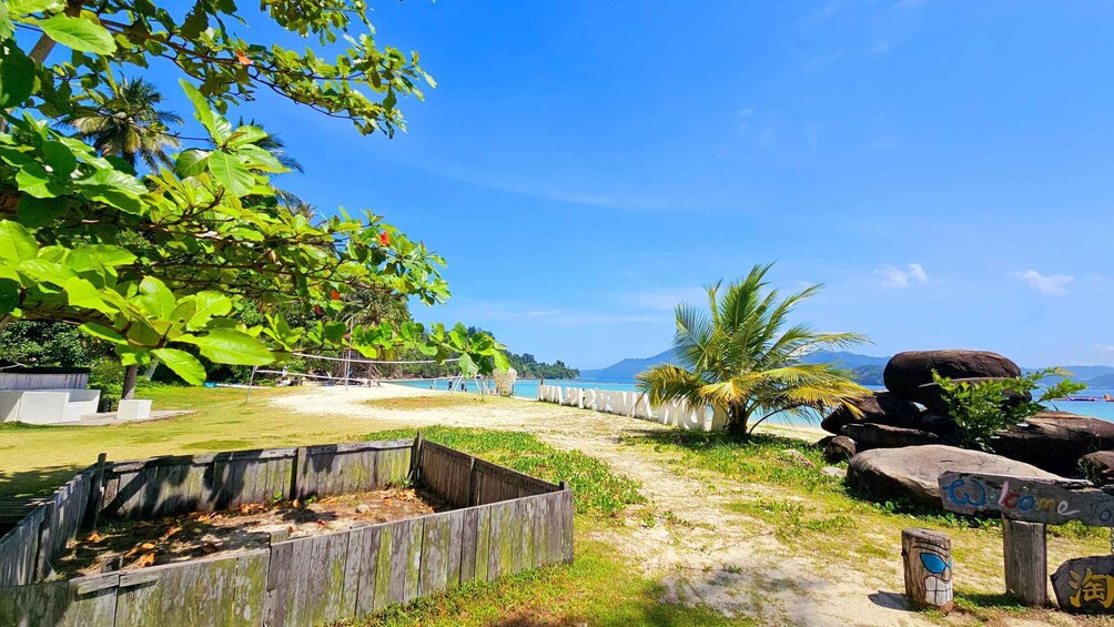 A beach with palm trees, a wooden fence, and a welcome sign. 5