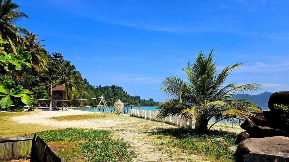 A beach volleyball court, palm trees, and a small hut. 2