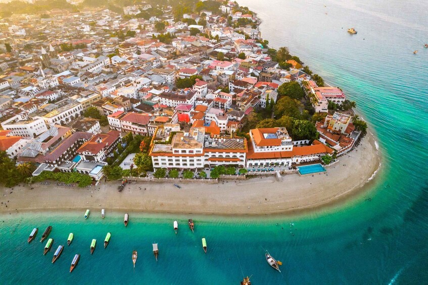 An aerial view of a coastal town with a beach, boats, and buildings. 2