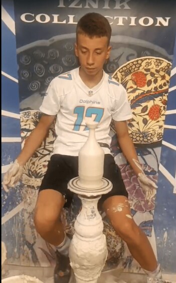 A person in a Dolphins jersey sitting on a chair with a white object in front of them. 2
