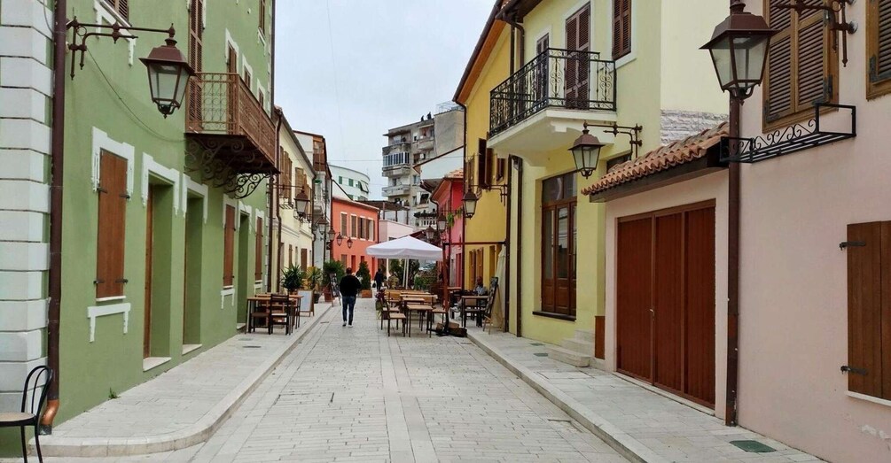 A narrow street lined with colorful buildings, outdoor seating, and traditional street lamps. 2
