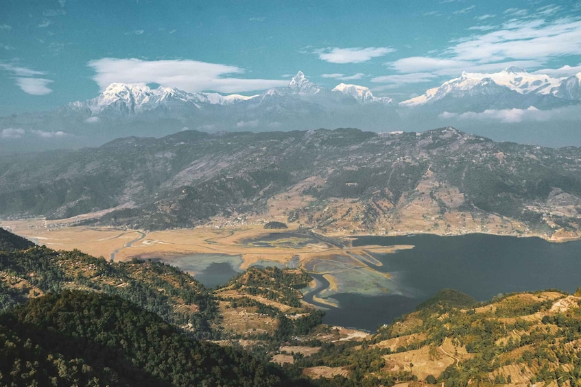 A mountainous landscape with a lake, a river, and snow-capped peaks in the distance. 3