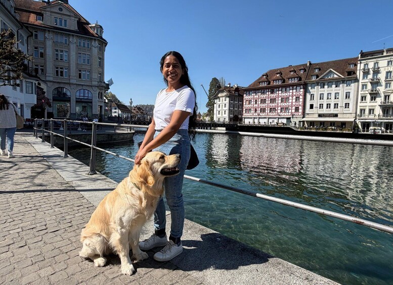 Una persona pasea con un perro por un camino pavimentado junto a un canal, con edificios históricos al fondo. 3