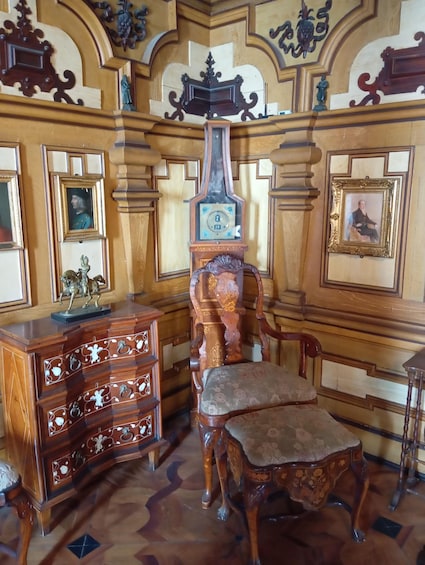 An ornate room with a wooden chair, a wooden cabinet, and a clock. 3
