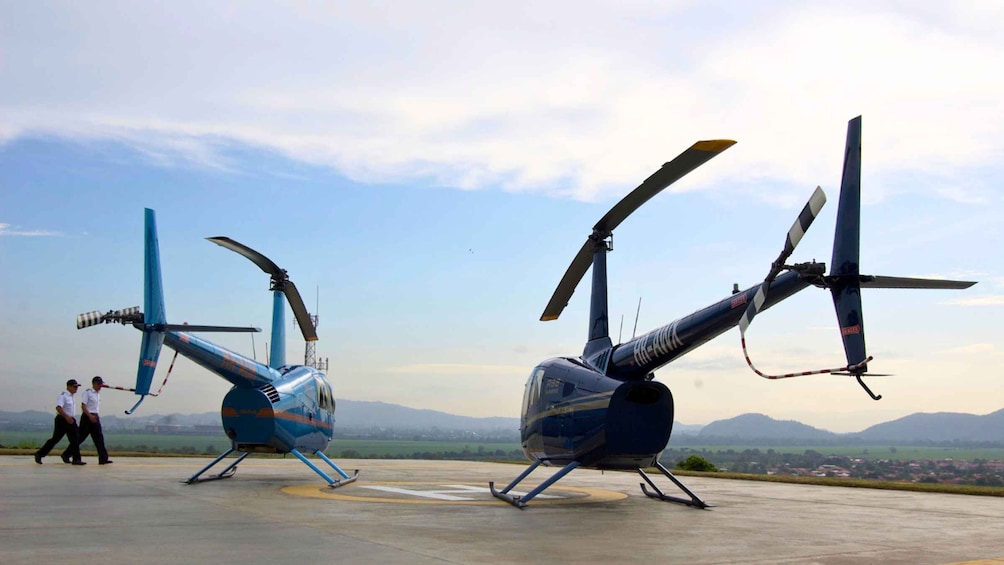 Two helicopters on a tarmac with mountains in the background. 4