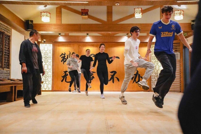 A dance class in a traditional room with wooden beams and tatami flooring. 3