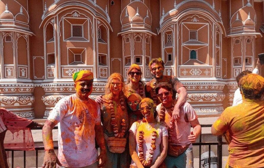 A group of people in front of a historic building with intricate white and orange patterns. 1