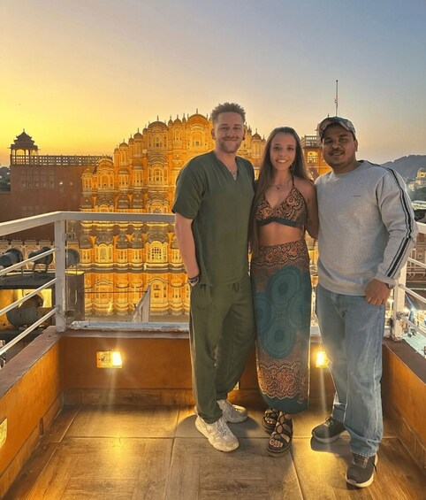 Three people standing on a balcony with a historic building in the background. 5