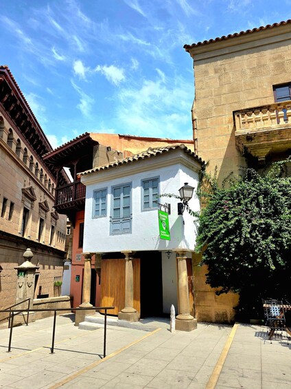 A street with a white building, a tree, and a sign reading 'Feria de la Salud.' 2