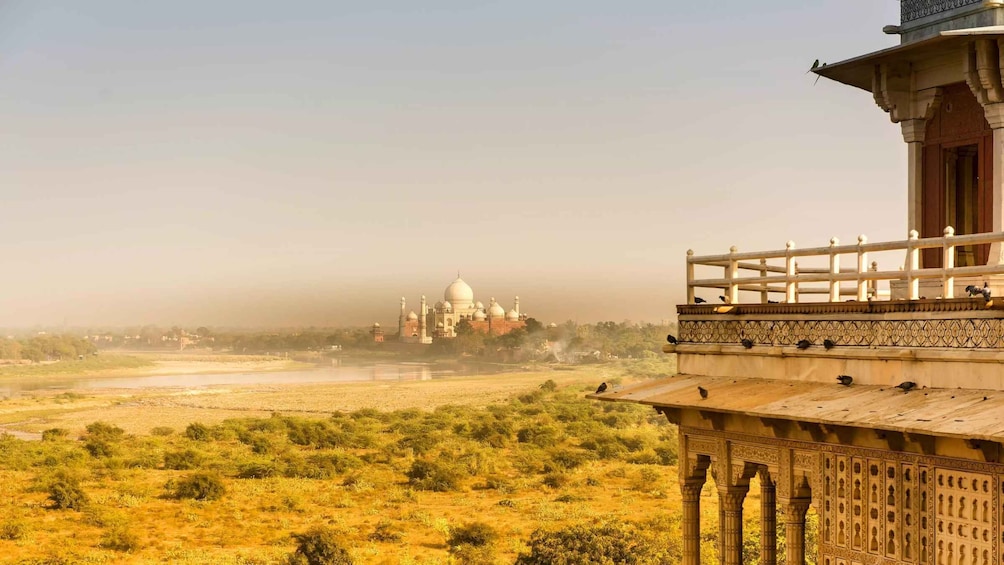 A view of the Taj Mahal with a foreground of a building with intricate carvings. 5