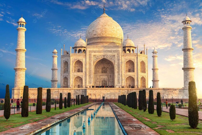 The Taj Mahal with four minarets and a central dome, surrounded by a symmetrical garden and a reflecting pool. 1