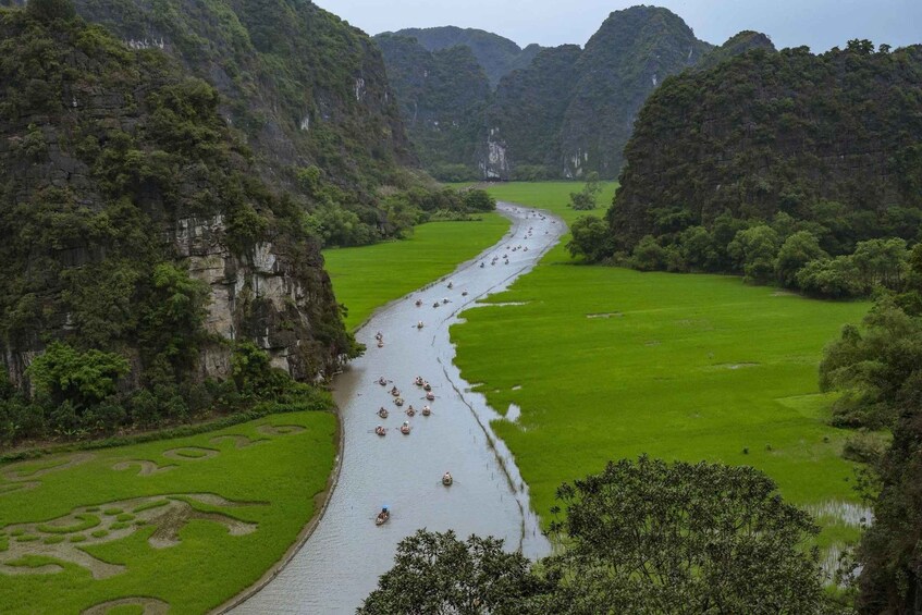 A river with people paddling boats, surrounded by lush green fields and steep cliffs. 3