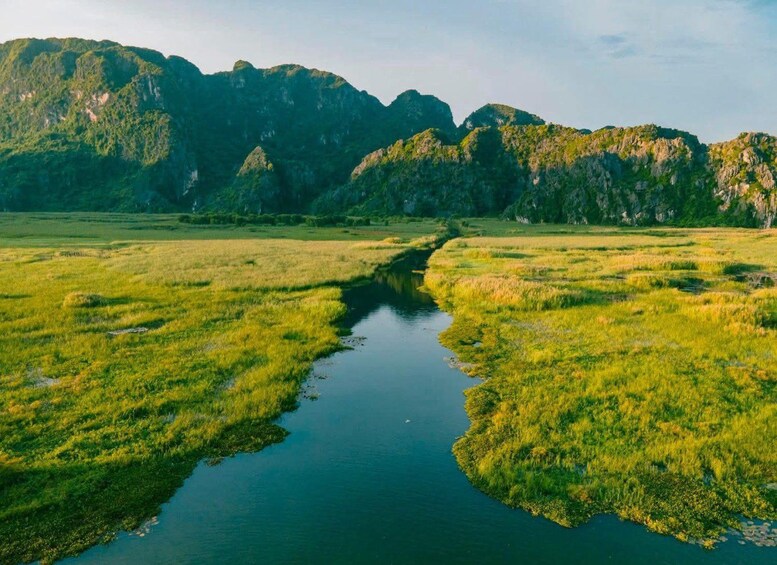 A river meandering through a grassy landscape with mountains in the background. 4