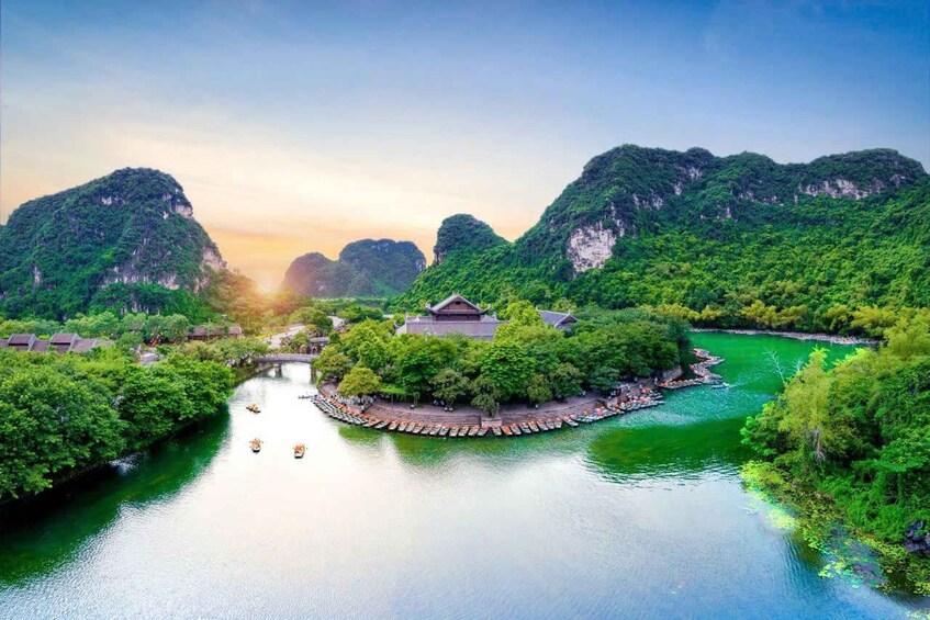 A river with boats, surrounded by lush greenery and traditional architecture. 1