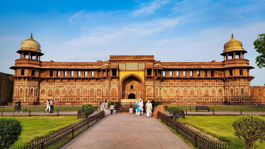 A large, ornate building with two domed towers, a central archway, and a pathway leading to the entrance. 2
