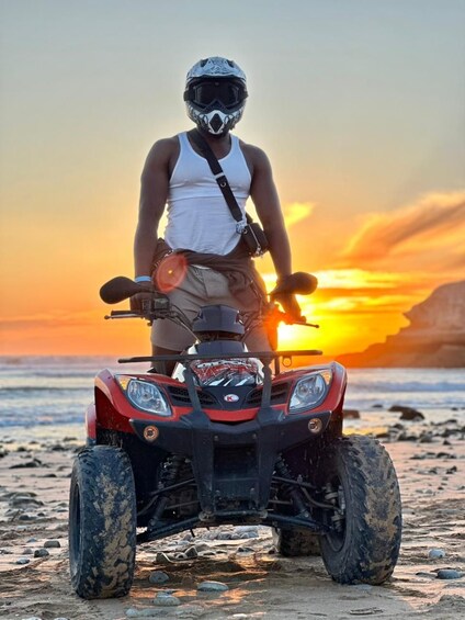 A person on a quad bike on a beach at sunset. 1