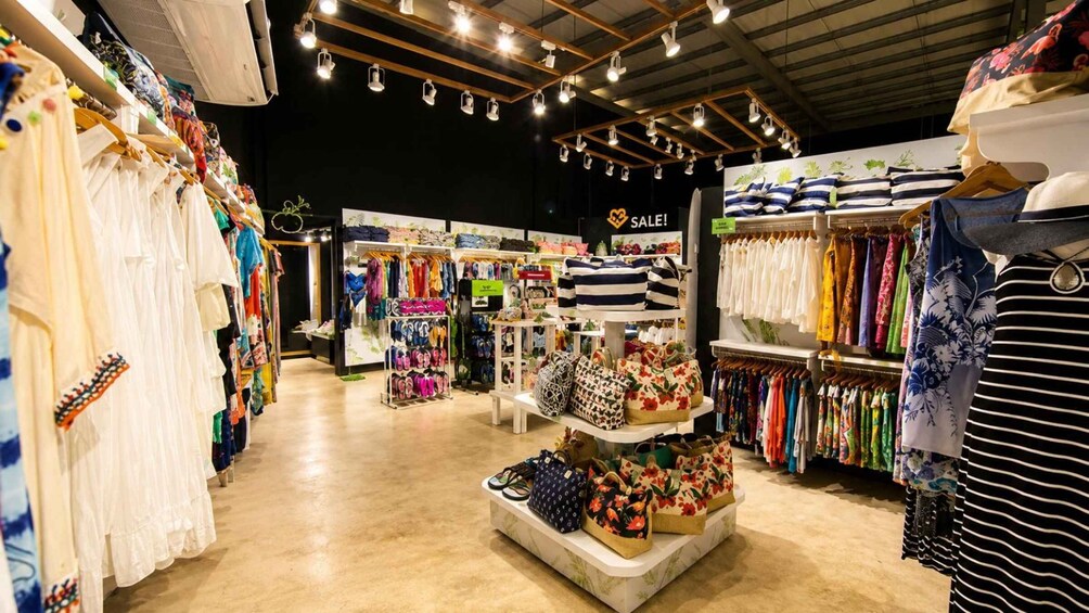 A clothing store with racks of dresses, a sale sign, and a display of bags. 4