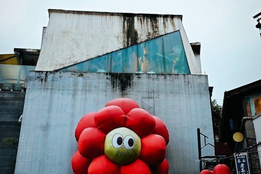 A red flower mural on a concrete wall with a blue graffiti section above it. 2