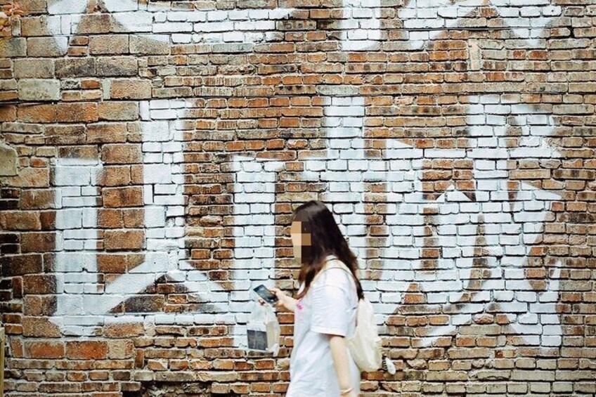 A person standing in front of a brick wall with graffiti. 5