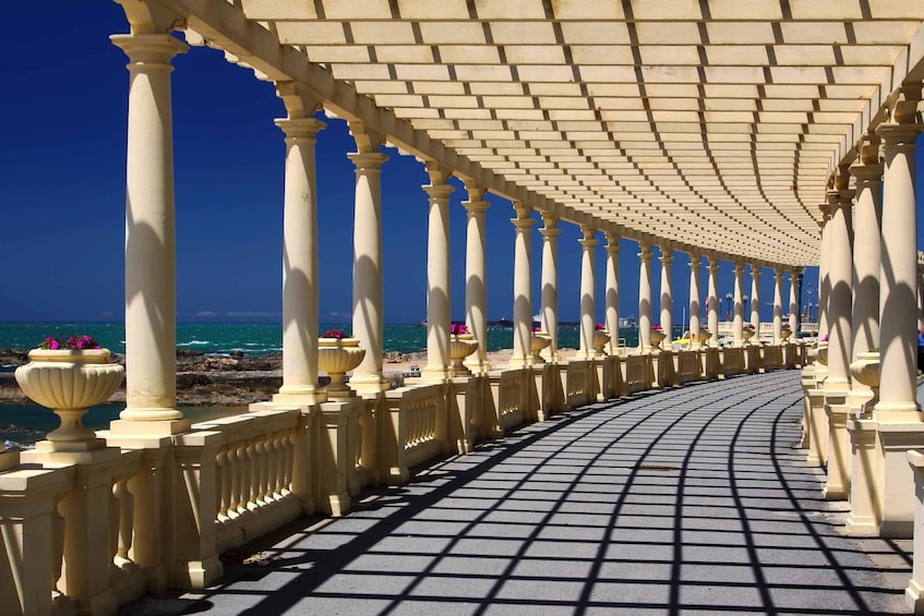 A seaside promenade with white columns and a tiled walkway. 3