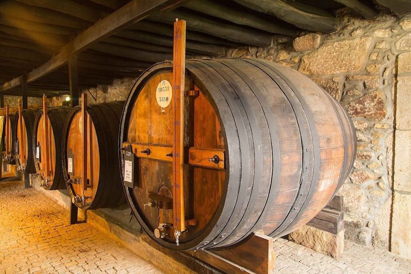 Wooden wine barrels in a cellar with stone walls. 4