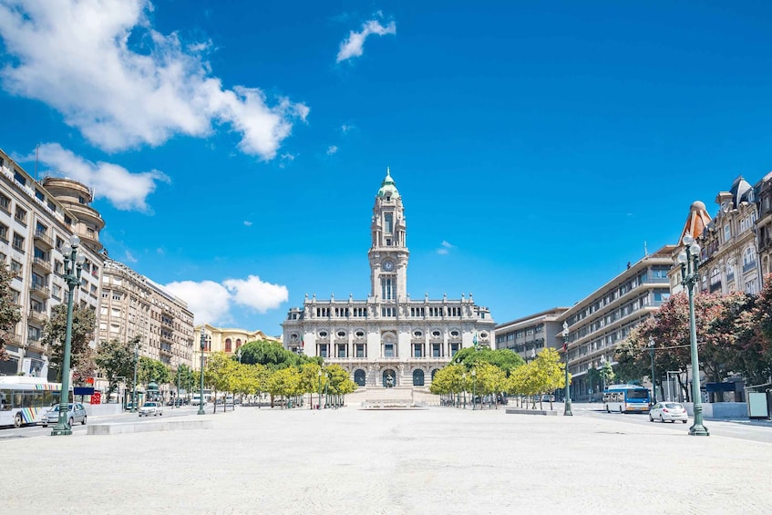 A historic building with a clock tower, surrounded by trees and a clear blue sky. 1