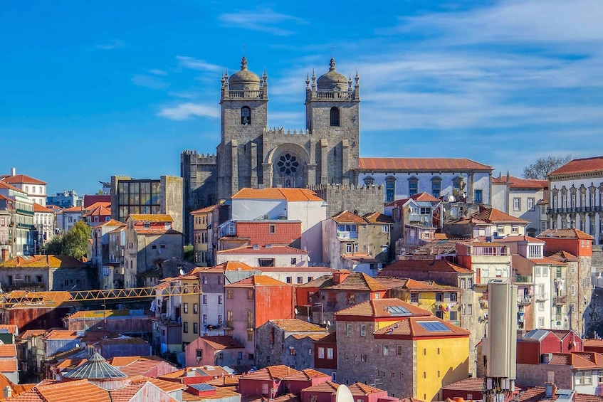A historic church with two towers, surrounded by colorful buildings and a clear blue sky. 5