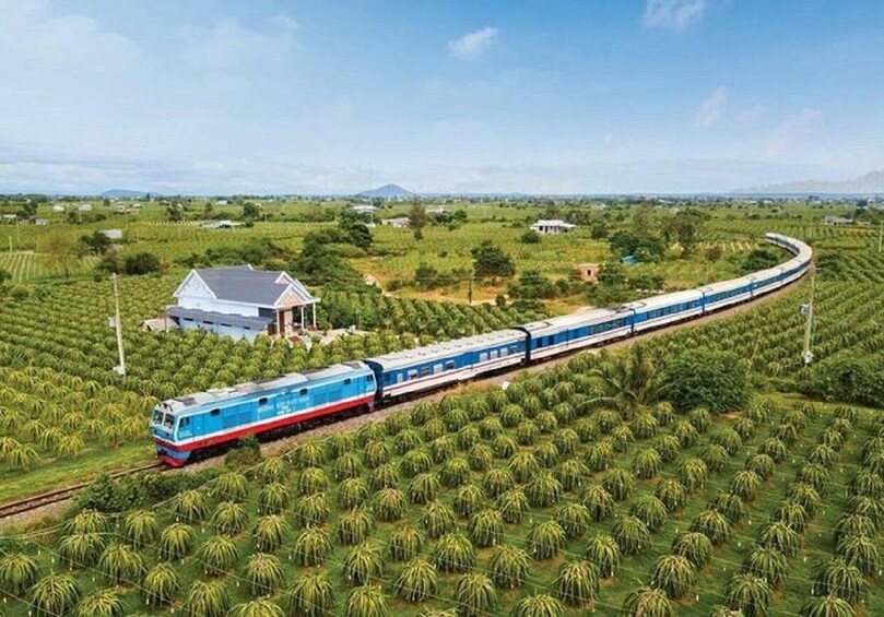 A train traveling through a lush green landscape with fields and a small house in the distance. 3