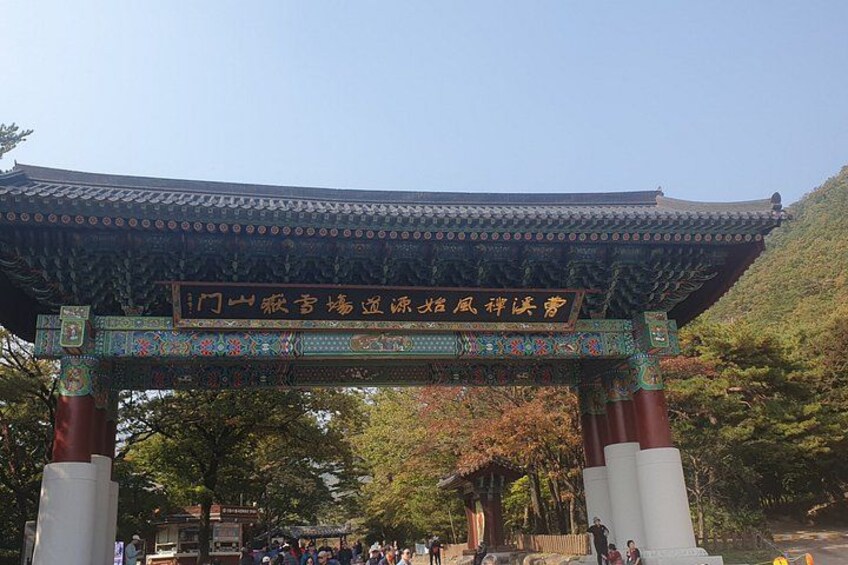 A traditional Korean gate with intricate designs and a signboard. 1