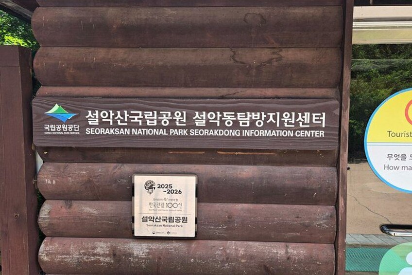 A wooden sign with Korean text and a plaque indicating the year 2025-2026. 4