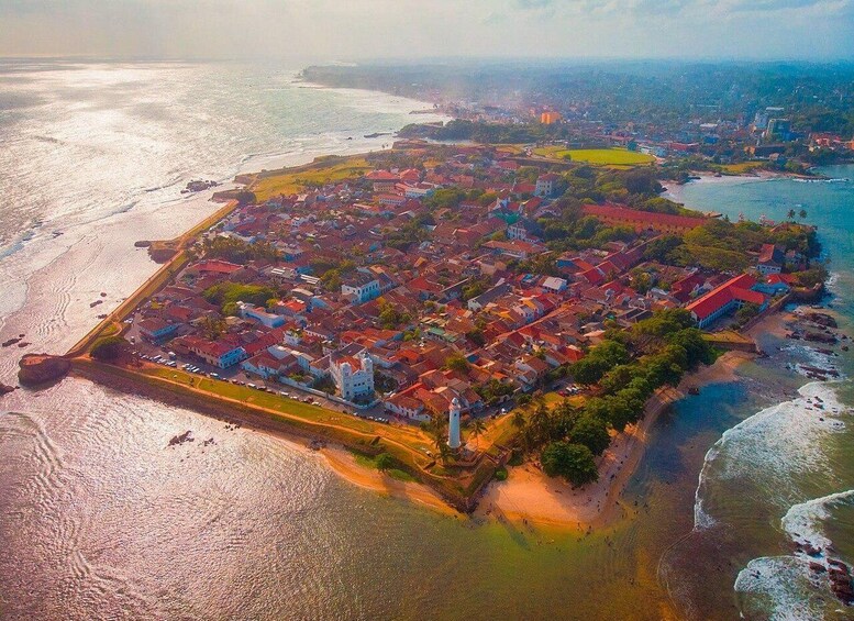An aerial view of a coastal town with a prominent fort, dense housing, and a beach. 2