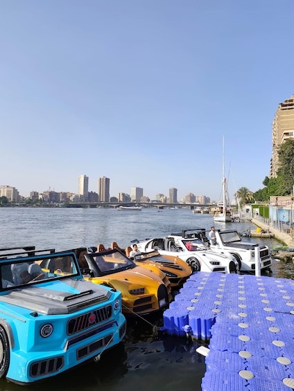 A waterfront with colorful boats docked, a city skyline in the background, and a clear blue sky. 4