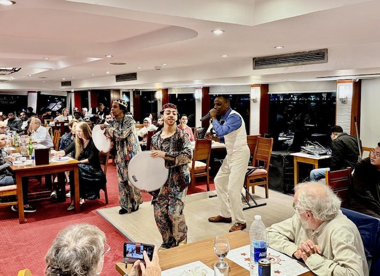 A group of people in a restaurant with tables, chairs, and a stage for a performance. 2