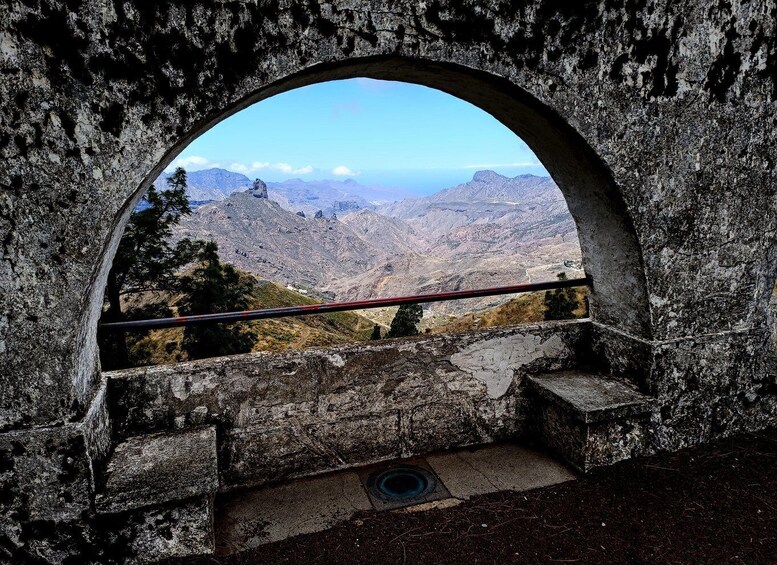 A stone archway with a view of a mountainous landscape. 2