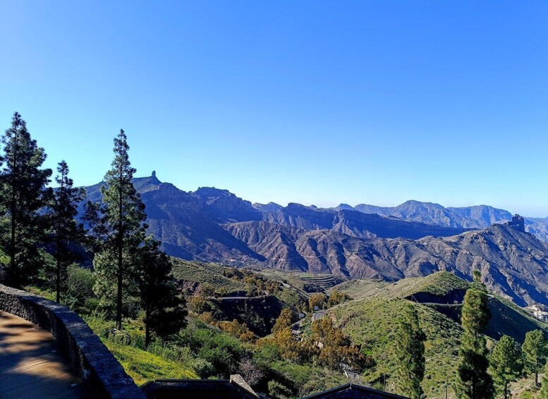A mountainous landscape with a winding road, dense trees, and distant peaks. 1