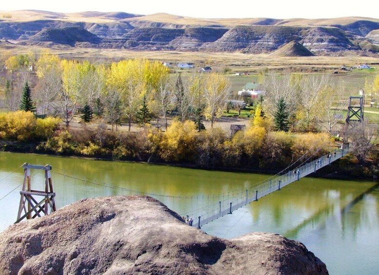 A suspension bridge over a river, surrounded by autumn-colored trees and a mountainous landscape. 3