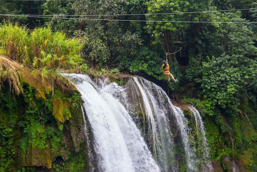 A person zip-lining over a waterfall surrounded by lush greenery. 3