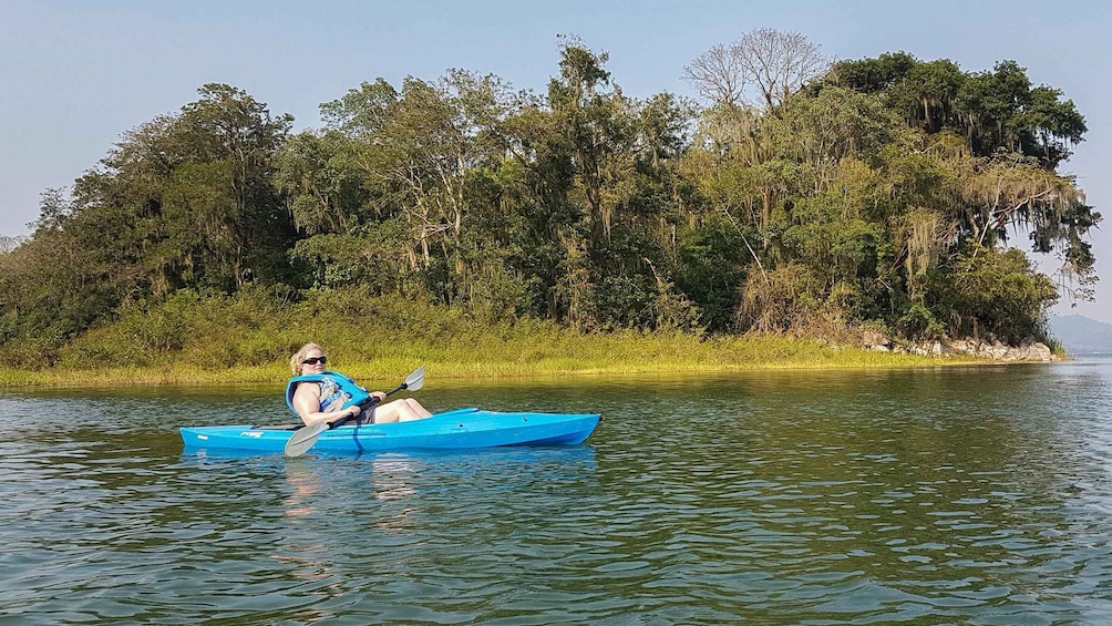A person kayaking on a calm river surrounded by dense forest. 2
