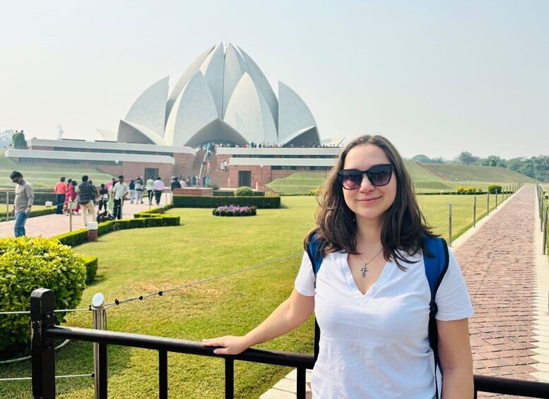 A person standing in front of a large, lotus-shaped building with a garden and a pathway. 3