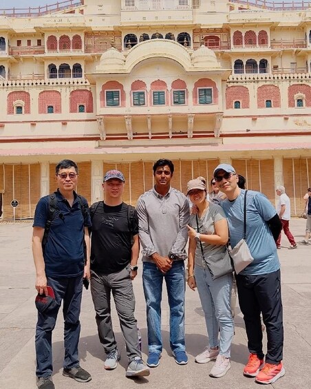A group of people standing in front of a historic building with arches and balconies. 5